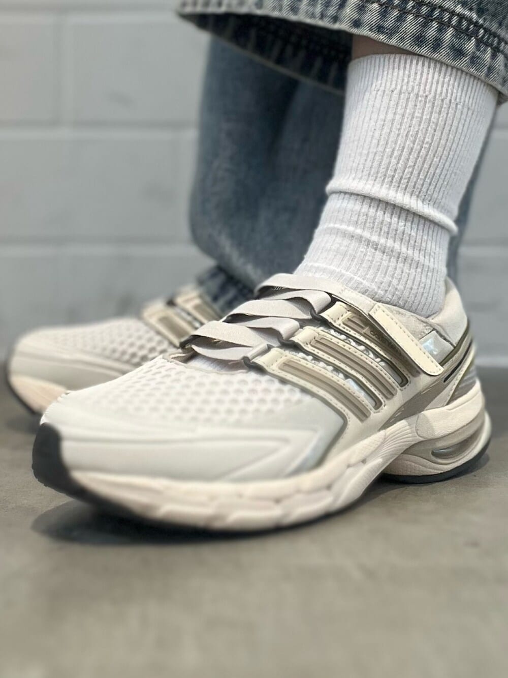 ブラック系のショルダーバッグ、ブルー系のデニムパンツ、ホワイト系のスニーカーを着用したレディースの春コーディネートの8枚目の写真