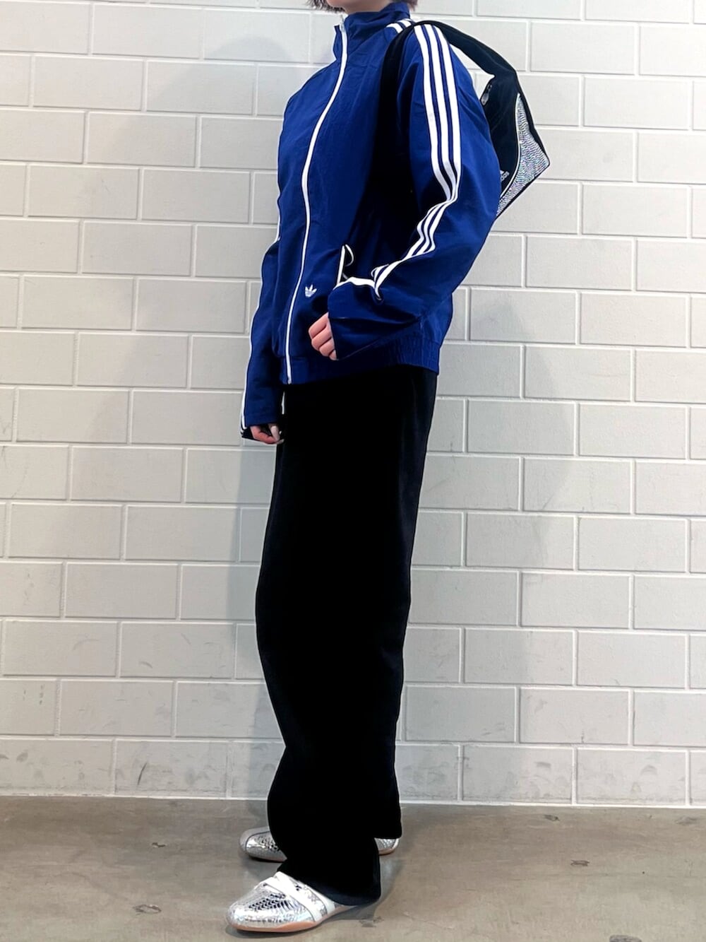 ブラック系のショルダーバッグ、シルバー系のスニーカー、ブルー系のナイロンジャケットを着用したレディースの春コーディネートの2枚目の写真