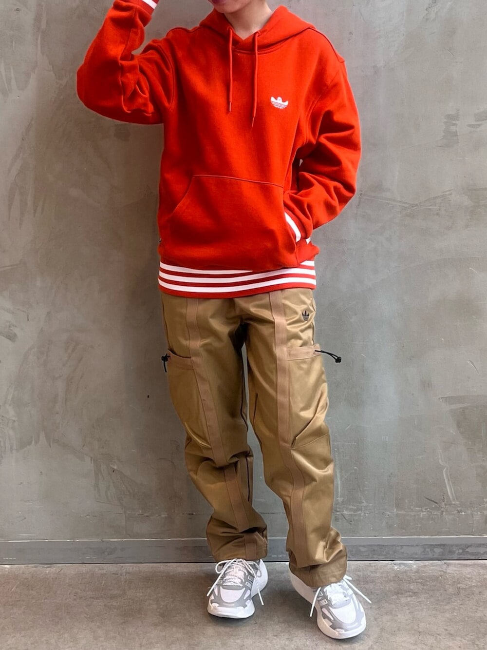 ブラウン系のカーゴパンツ、ホワイト系のシューズ、オレンジ系のパーカーを着用したレディースの冬コーディネートの3枚目の写真