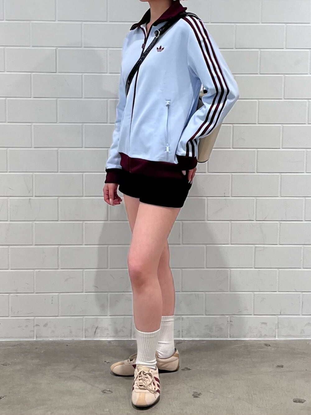 ベージュ系のショルダーバッグ、グリーン系のスニーカー、ブルー系のジャージを着用したレディースの春コーディネートの2枚目の写真