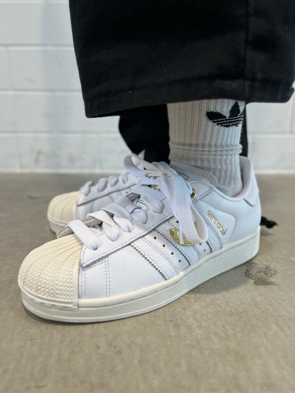 ブラック系のデニムジャケット、ホワイト系のスニーカー、ブルー系のアクセサリーを着用したレディースの春コーディネートの6枚目の写真