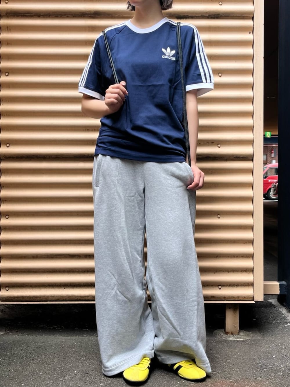 ブラック系のエコバッグ/サブバッグ、ブルー系のTシャツ/カットソー、イエロー系のスニーカーを着用したレディースの夏コーディネートの2枚目の写真