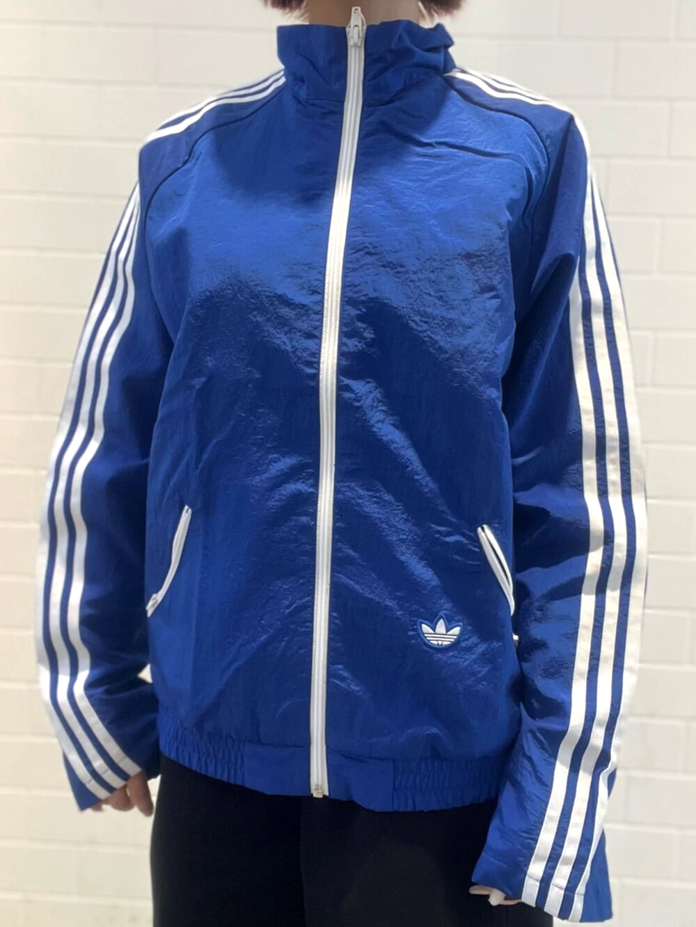 ブラック系のショルダーバッグ、シルバー系のスニーカー、ブルー系のナイロンジャケットを着用したレディースの春コーディネートの4枚目の写真