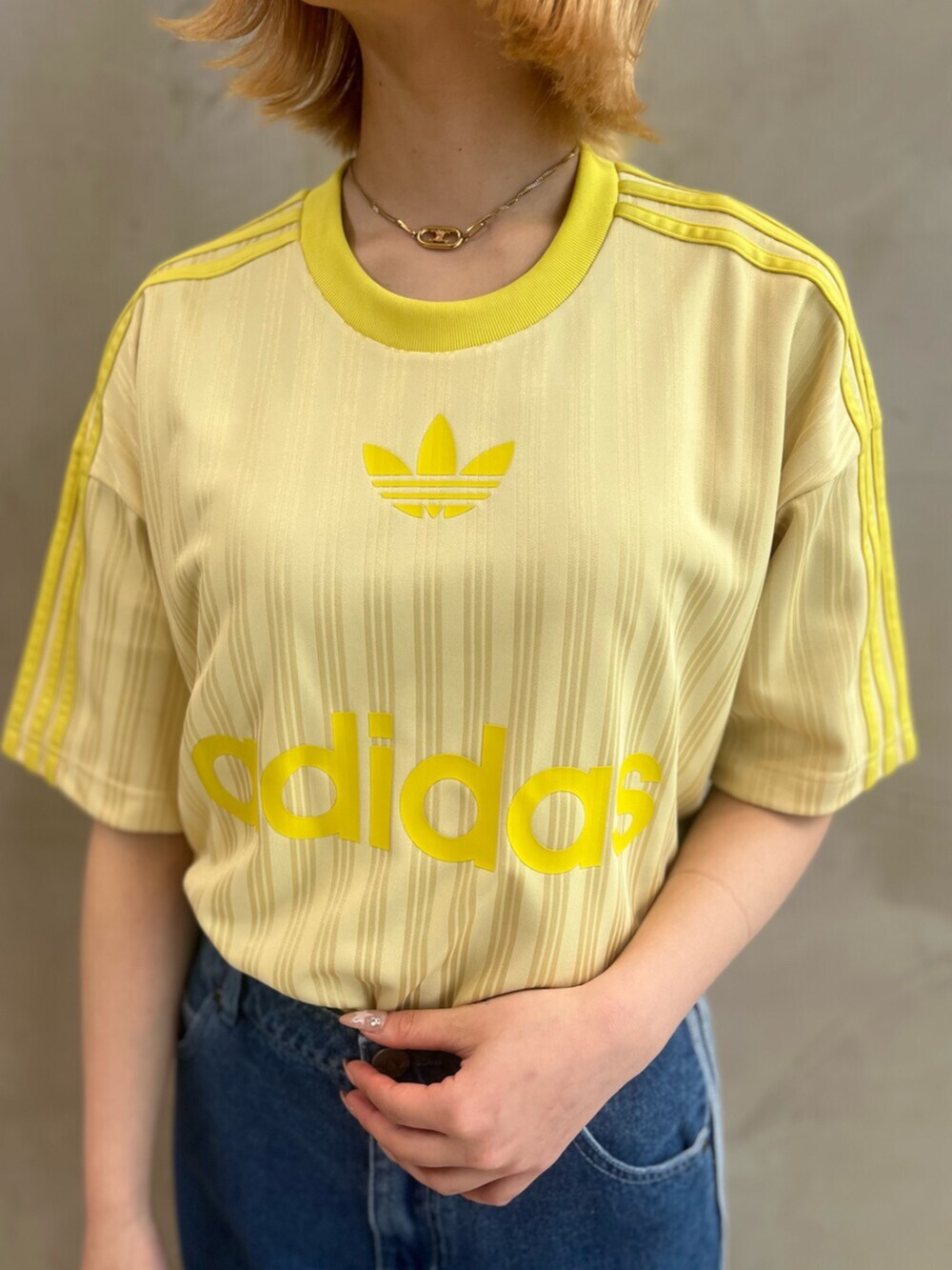 イエロー系のスニーカー、イエロー系のトップス、ブルー系のデニムパンツを着用したレディースの春コーディネートの5枚目の写真