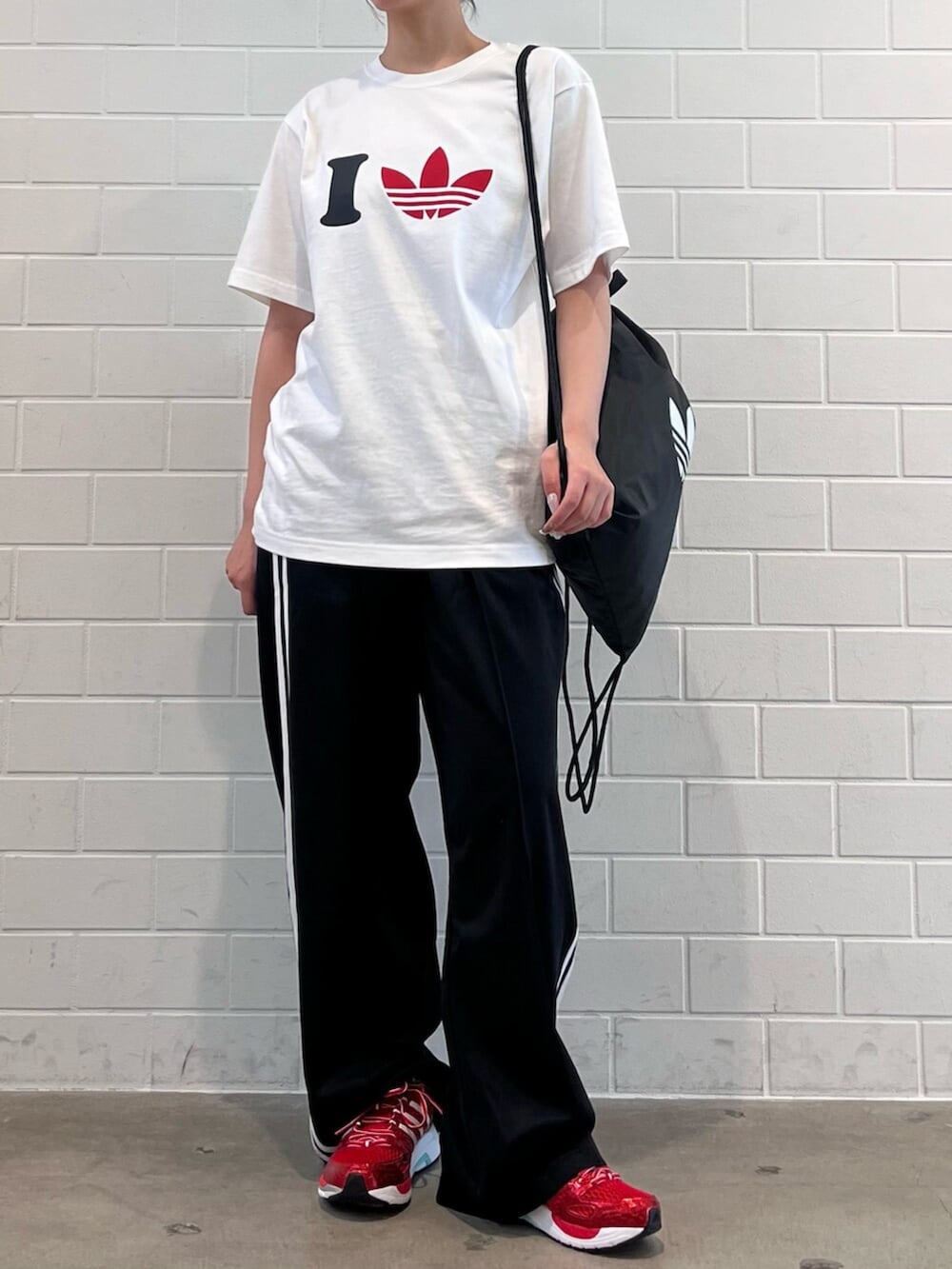 ブラック系のエコバッグ/サブバッグ、レッド系のスニーカー、ホワイト系のTシャツ/カットソーを着用したレディースの夏コーディネートの2枚目の写真