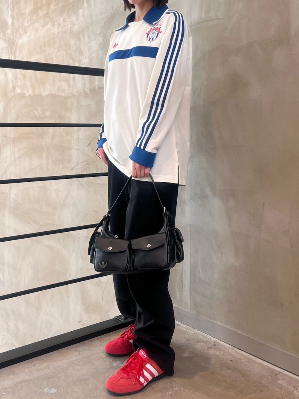 レッド系のスニーカー、ブラック系のショルダーバッグ、ホワイト系のポロシャツを着用したレディースの春コーディネートの2枚目の写真