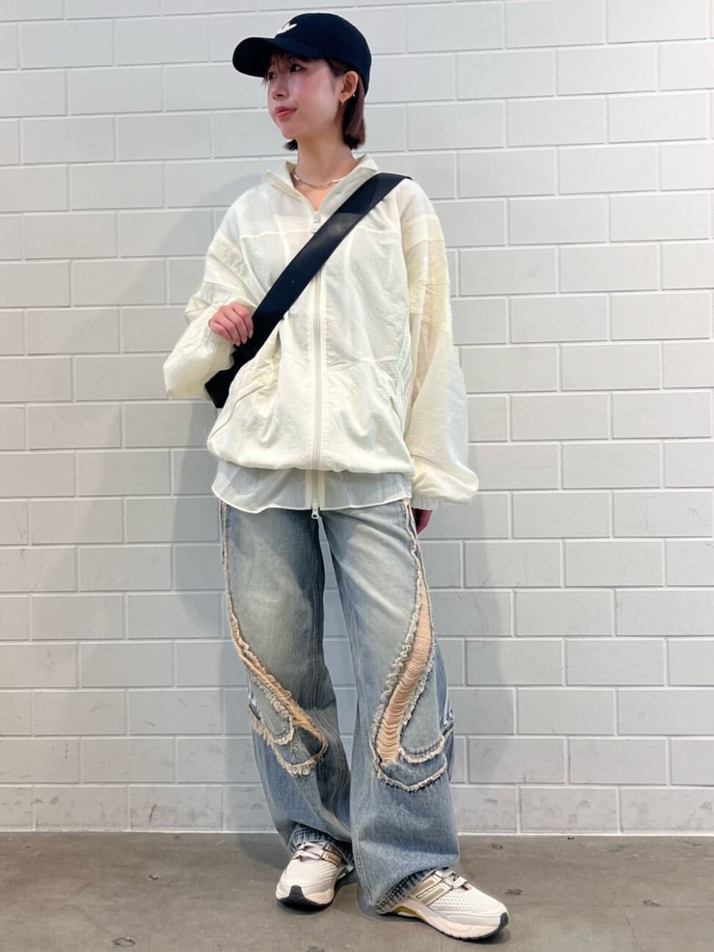 ブラック系のショルダーバッグ、ブルー系のデニムパンツ、ホワイト系のスニーカーを着用したレディースの春コーディネートの3枚目の写真