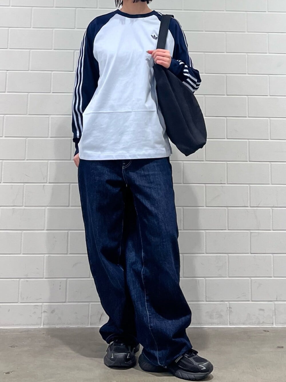 ブラック系のスニーカー、ブルー系のTシャツ/カットソー、ブラック系のトートバッグを着用したレディースの冬コーディネートの2枚目の写真