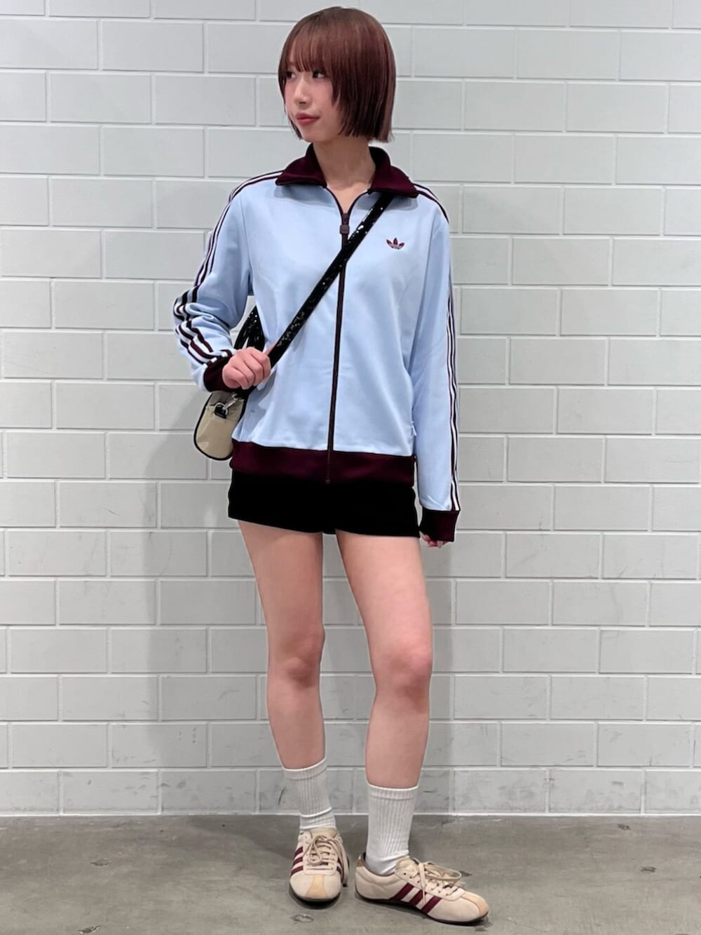 ベージュ系のショルダーバッグ、グリーン系のスニーカー、ブルー系のジャージを着用したレディースの春コーディネートの3枚目の写真