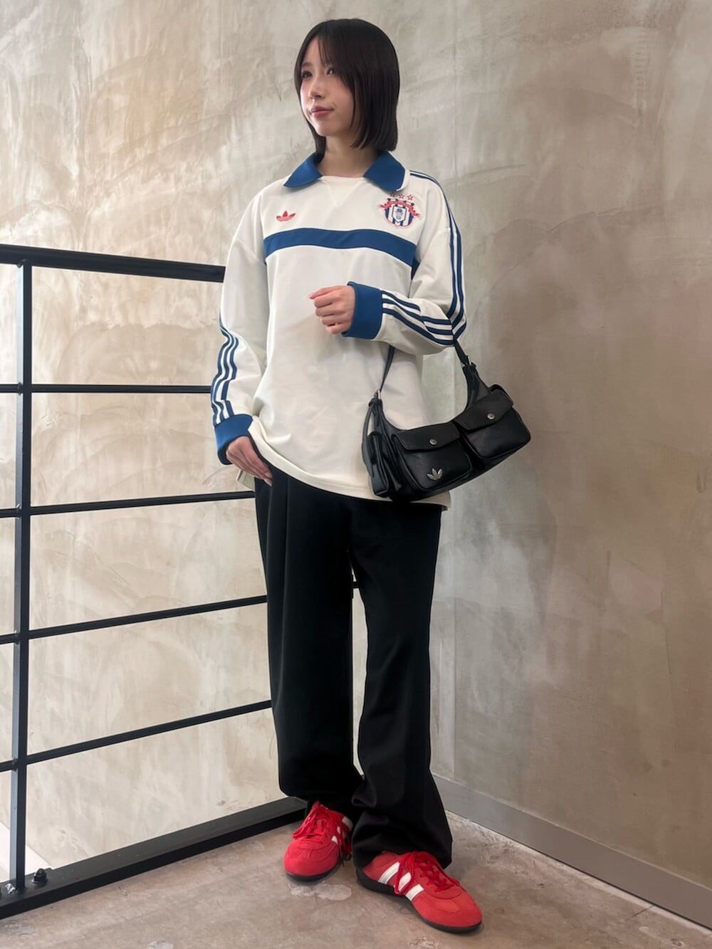 レッド系のスニーカー、ブラック系のショルダーバッグ、ホワイト系のポロシャツを着用したレディースの春コーディネートの3枚目の写真