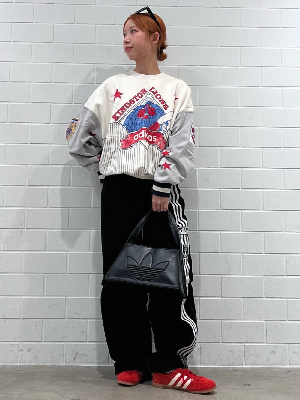 ブラック系のショルダーバッグ、レッド系のスニーカー、ブラック系のデニムパンツを着用したレディースの秋コーディネートの3枚目の写真