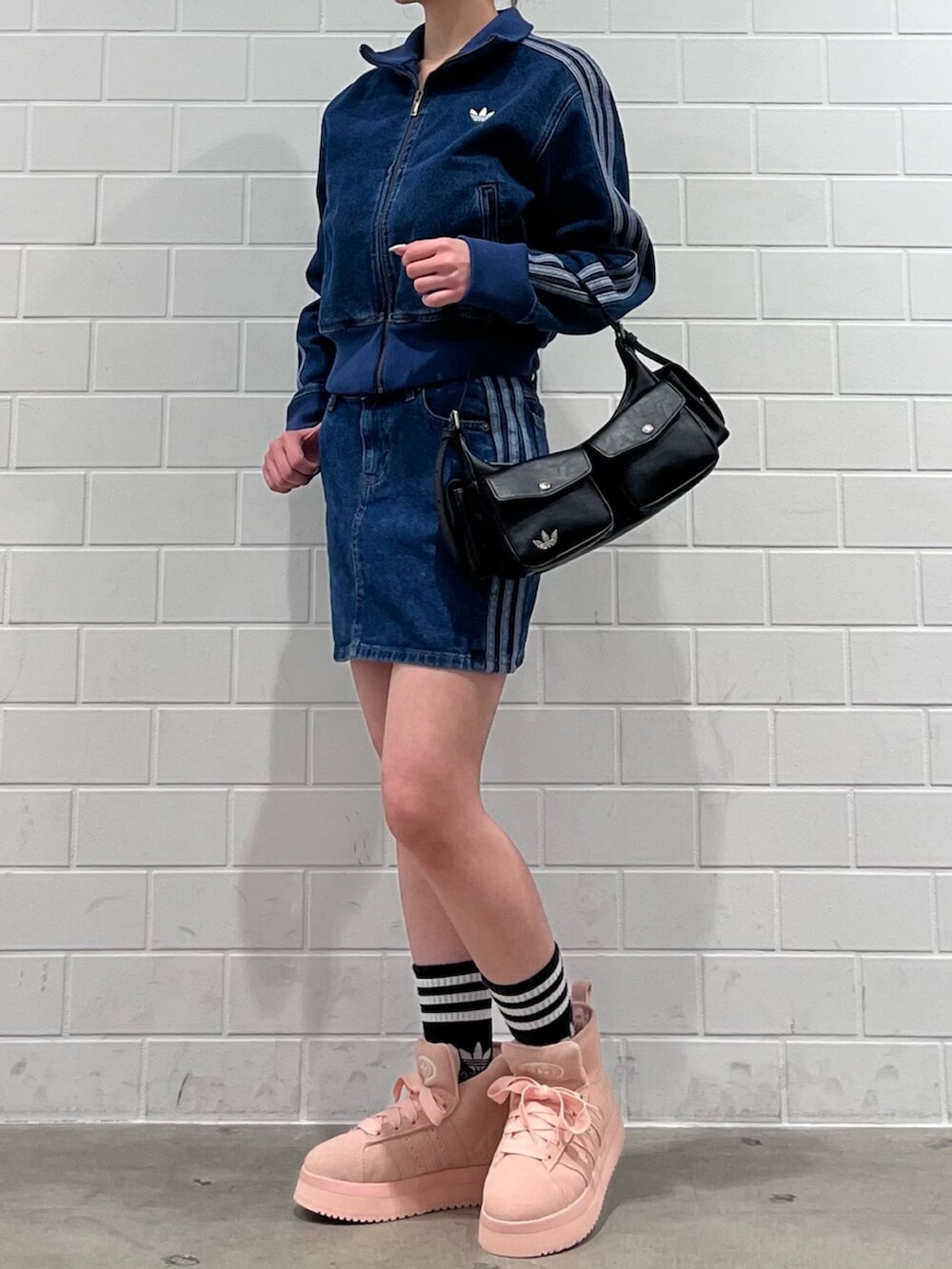 ブラック系のショルダーバッグ、ピンク系のシューズ、ブルー系のジャージを着用したレディースの冬コーディネートの2枚目の写真