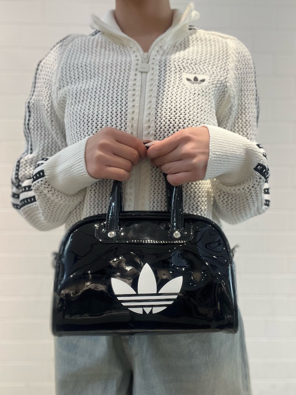 ブラック系のショルダーバッグ、ブラック系のスニーカー、ブルー系のデニムパンツを着用したレディースの春コーディネートの6枚目の写真