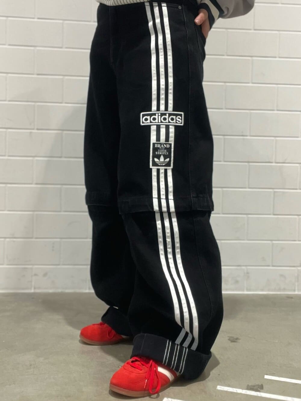 ブラック系のショルダーバッグ、レッド系のスニーカー、ブラック系のデニムパンツを着用したレディースの秋コーディネートの7枚目の写真