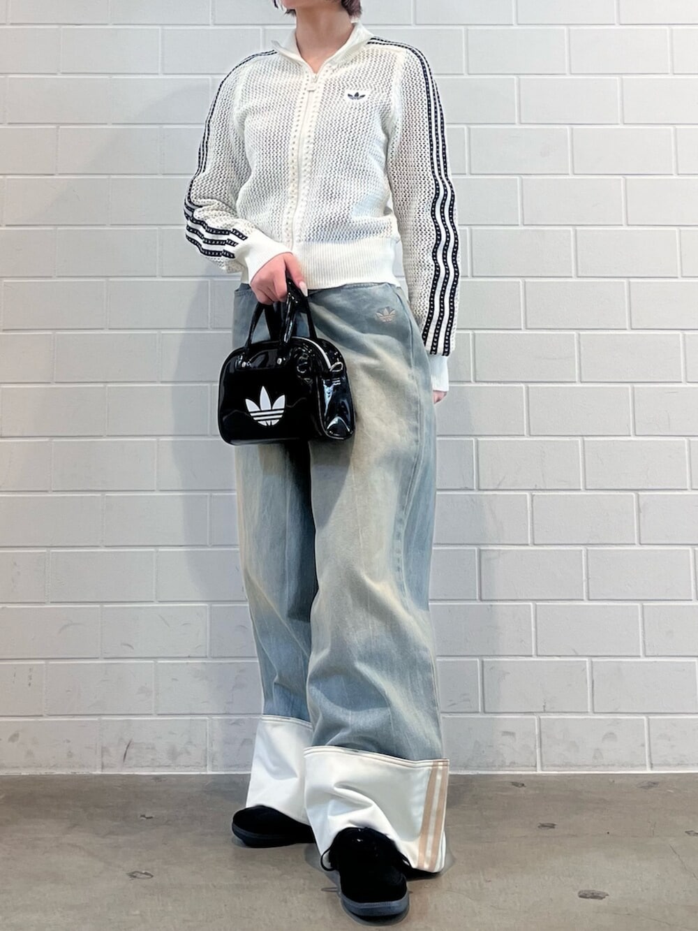 ブラック系のショルダーバッグ、ブラック系のスニーカー、ブルー系のデニムパンツを着用したレディースの春コーディネートの2枚目の写真