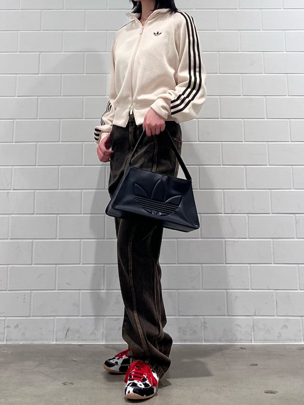 ブラック系のショルダーバッグ、ホワイト系のジャージ、ブラウン系のパンツを着用したレディースの冬コーディネートの2枚目の写真