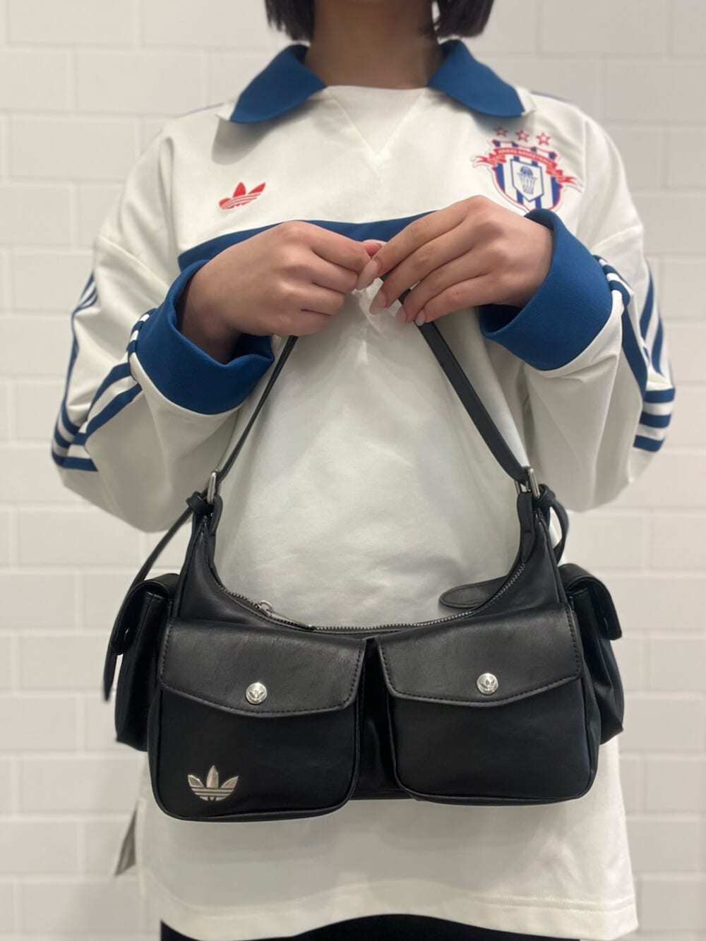 レッド系のスニーカー、ブラック系のショルダーバッグ、ホワイト系のポロシャツを着用したレディースの春コーディネートの5枚目の写真