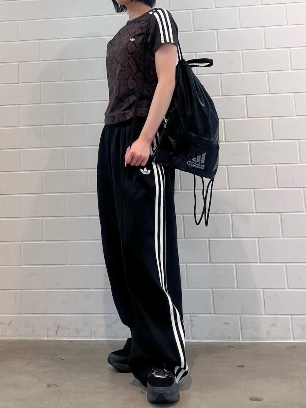 ブラック系のスニーカー、ブラック系のエコバッグ/サブバッグ、ブラウン系のTシャツ/カットソーを着用したレディースの夏コーディネートの2枚目の写真