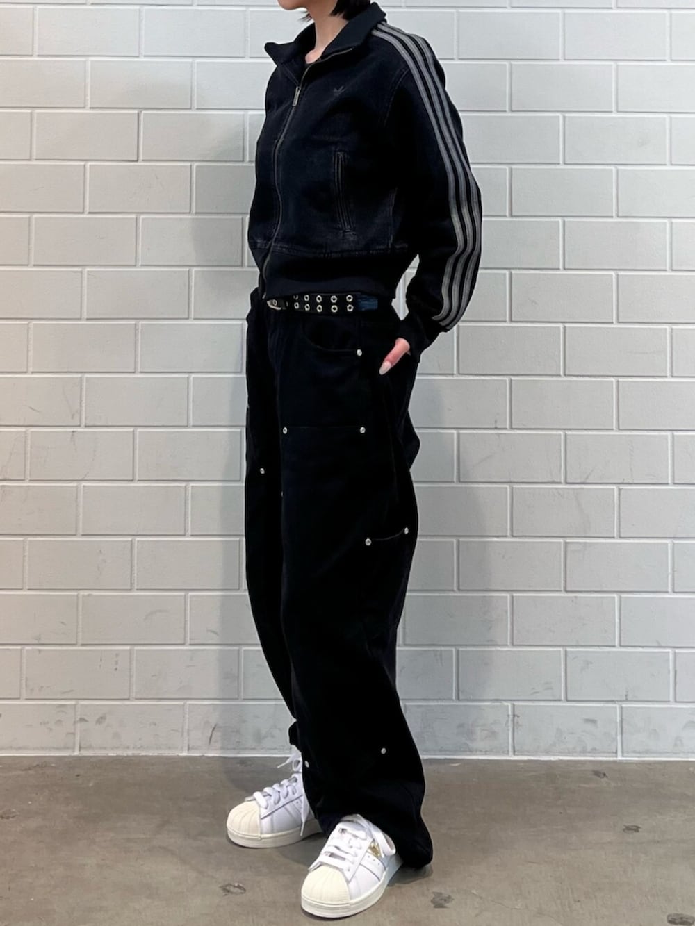 ブラック系のデニムジャケット、ホワイト系のスニーカー、ブルー系のアクセサリーを着用したレディースの春コーディネートの2枚目の写真