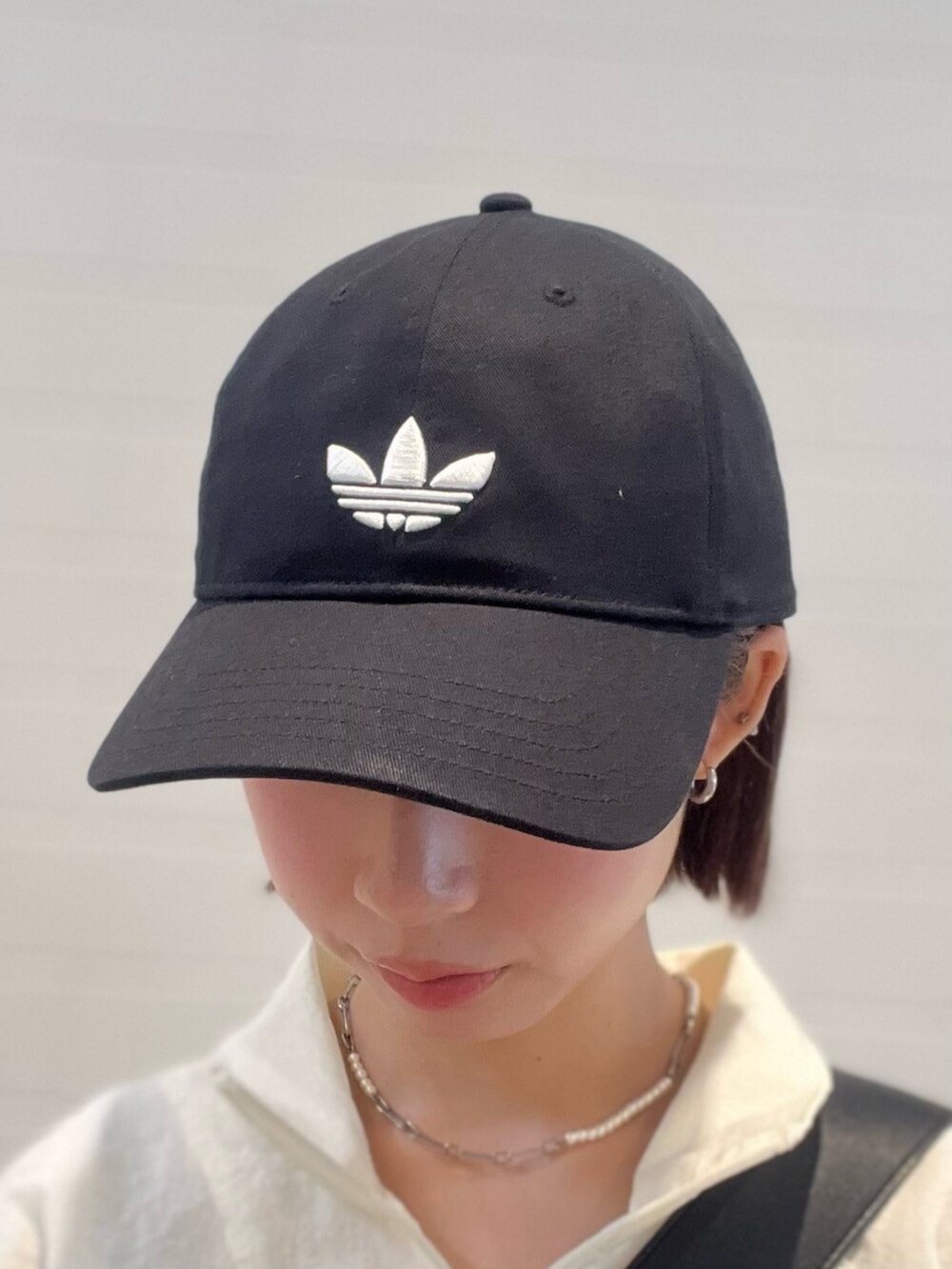 ブラック系のショルダーバッグ、ブルー系のデニムパンツ、ホワイト系のスニーカーを着用したレディースの春コーディネートの4枚目の写真