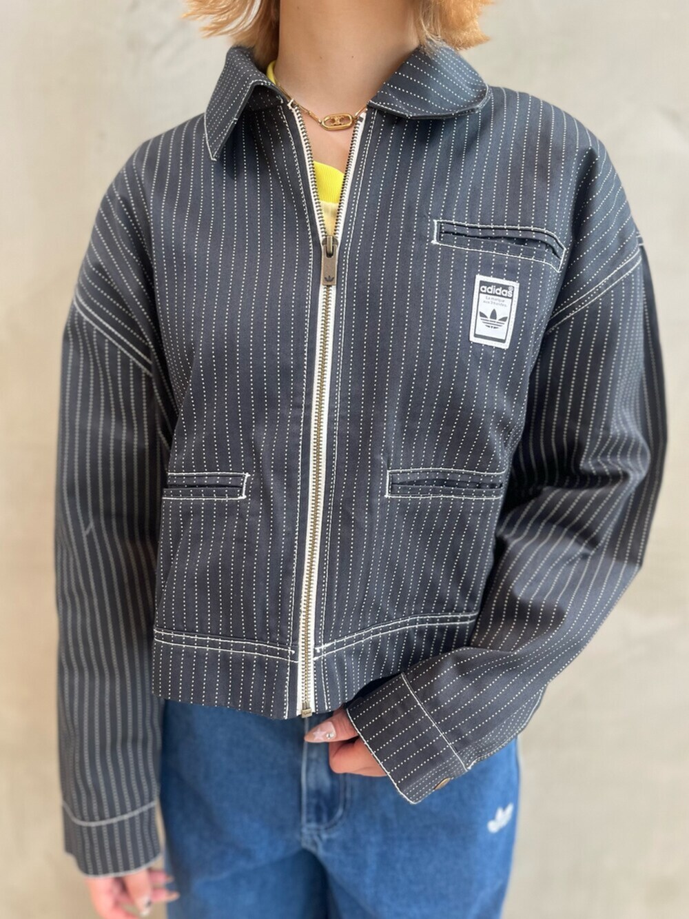イエロー系のスニーカー、イエロー系のトップス、ブルー系のデニムパンツを着用したレディースの春コーディネートの4枚目の写真