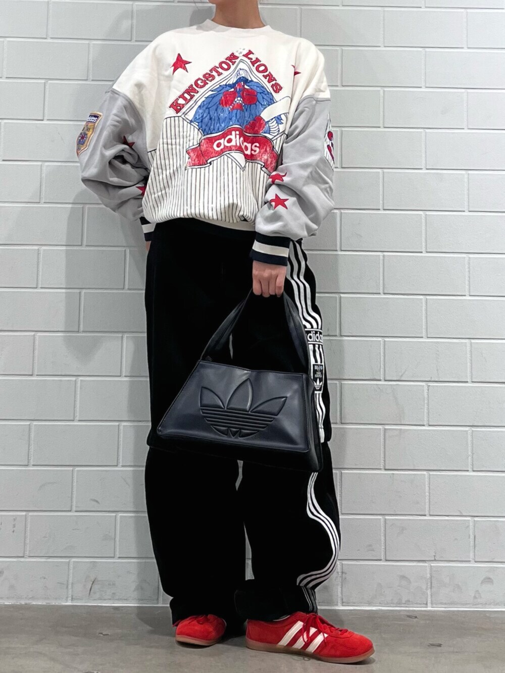 ブラック系のショルダーバッグ、レッド系のスニーカー、ブラック系のデニムパンツを着用したレディースの秋コーディネートの2枚目の写真