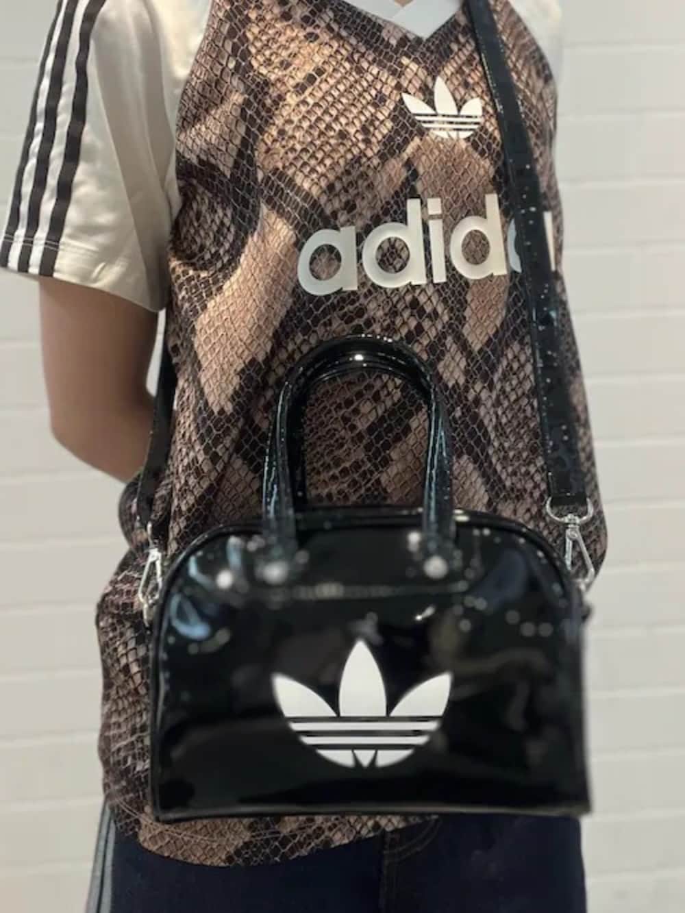 ブラック系のショルダーバッグ、ブルー系のデニムパンツ、ブラック系のスニーカーを着用したレディースの夏コーディネートの4枚目の写真