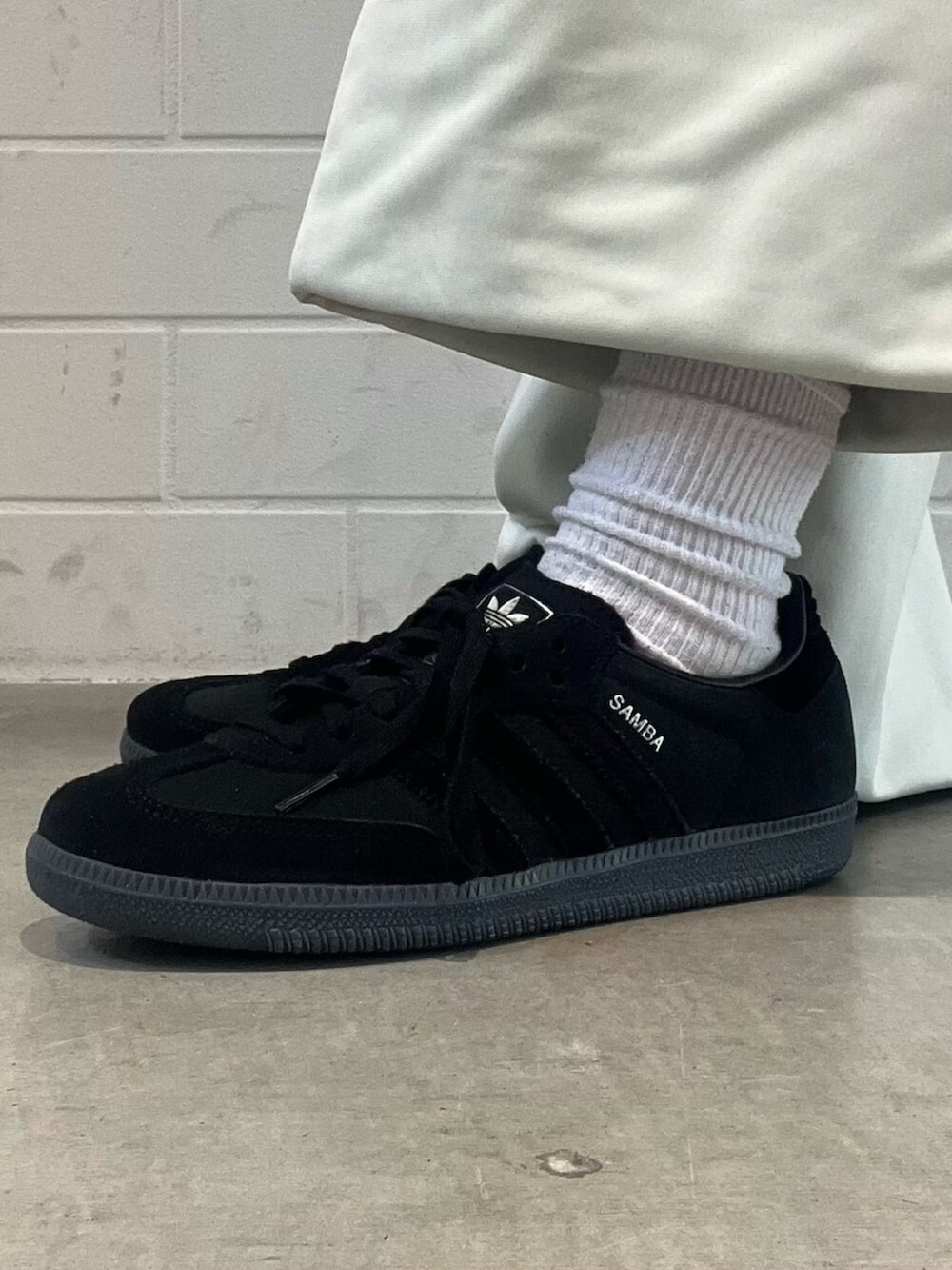 ブラック系のショルダーバッグ、ブラック系のスニーカー、ブルー系のデニムパンツを着用したレディースの春コーディネートの8枚目の写真