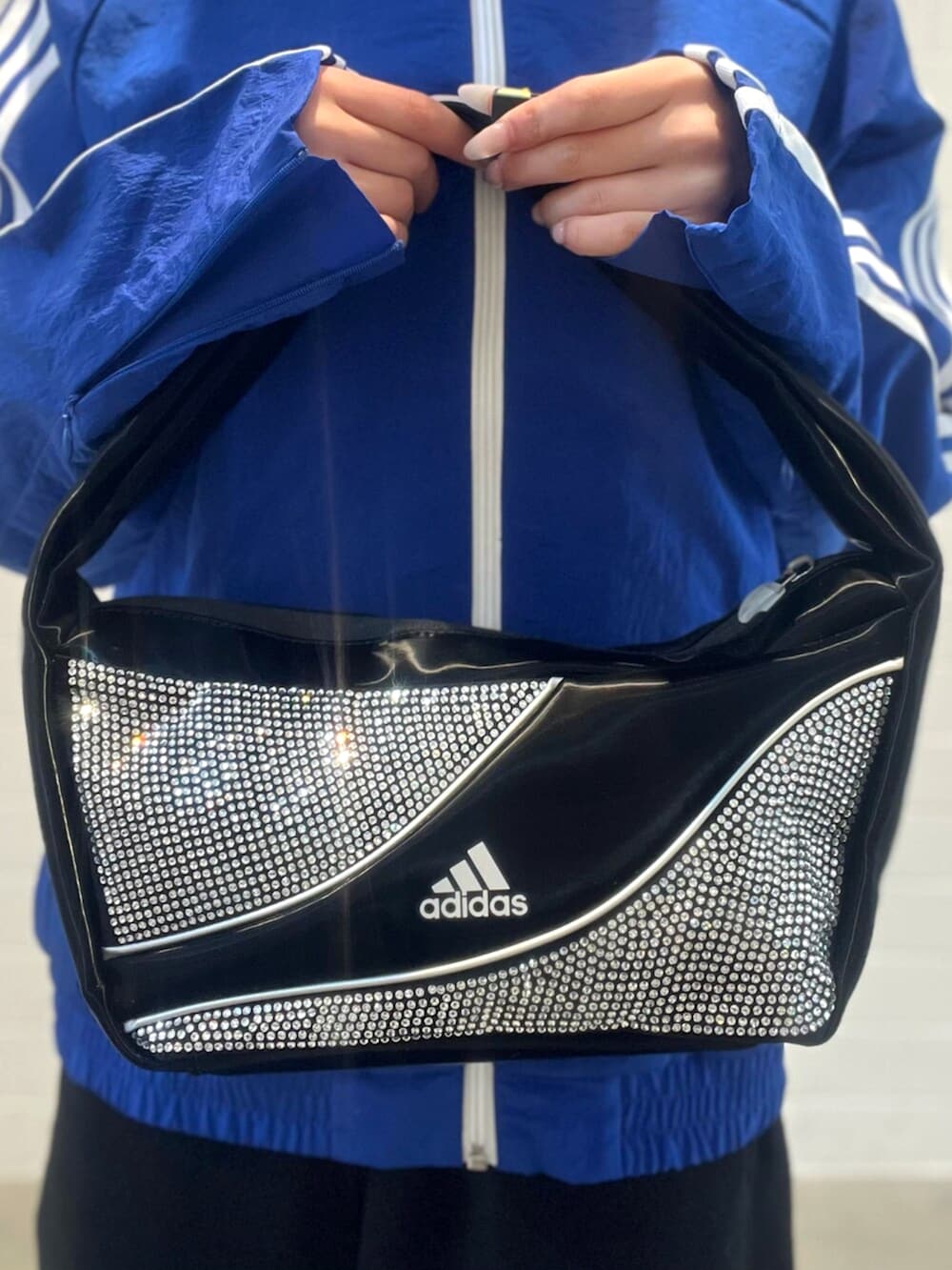 ブラック系のショルダーバッグ、シルバー系のスニーカー、ブルー系のナイロンジャケットを着用したレディースの春コーディネートの5枚目の写真