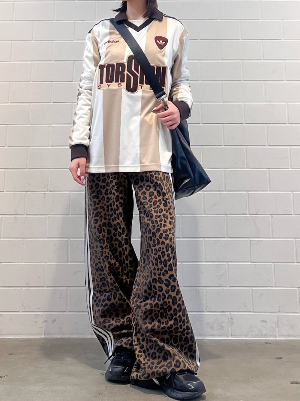 ブラック系のショルダーバッグ、ブラック系のスニーカー、ホワイト系のトップスを着用したレディースの冬コーディネートの2枚目の写真