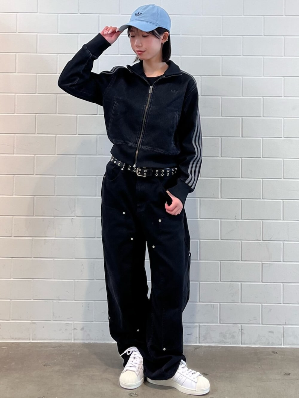 ブラック系のデニムジャケット、ホワイト系のスニーカー、ブルー系のアクセサリーを着用したレディースの春コーディネートの3枚目の写真