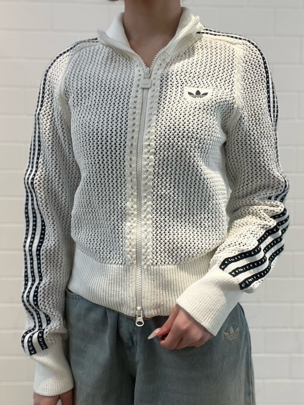 ブラック系のショルダーバッグ、ブラック系のスニーカー、ブルー系のデニムパンツを着用したレディースの春コーディネートの5枚目の写真