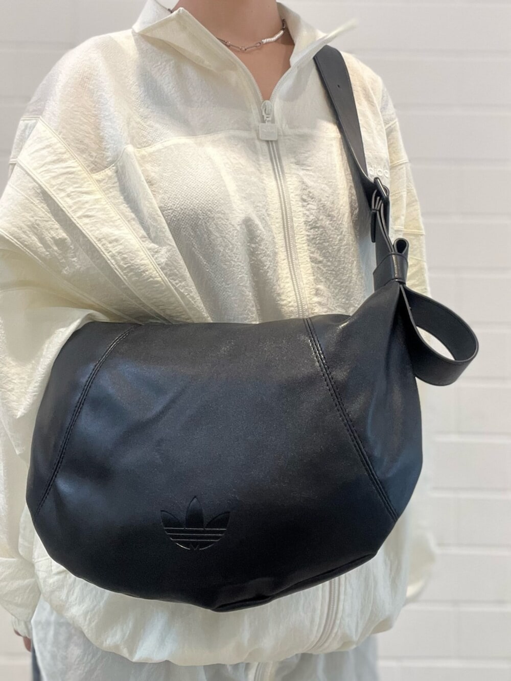 ブラック系のショルダーバッグ、ブルー系のデニムパンツ、ホワイト系のスニーカーを着用したレディースの春コーディネートの6枚目の写真