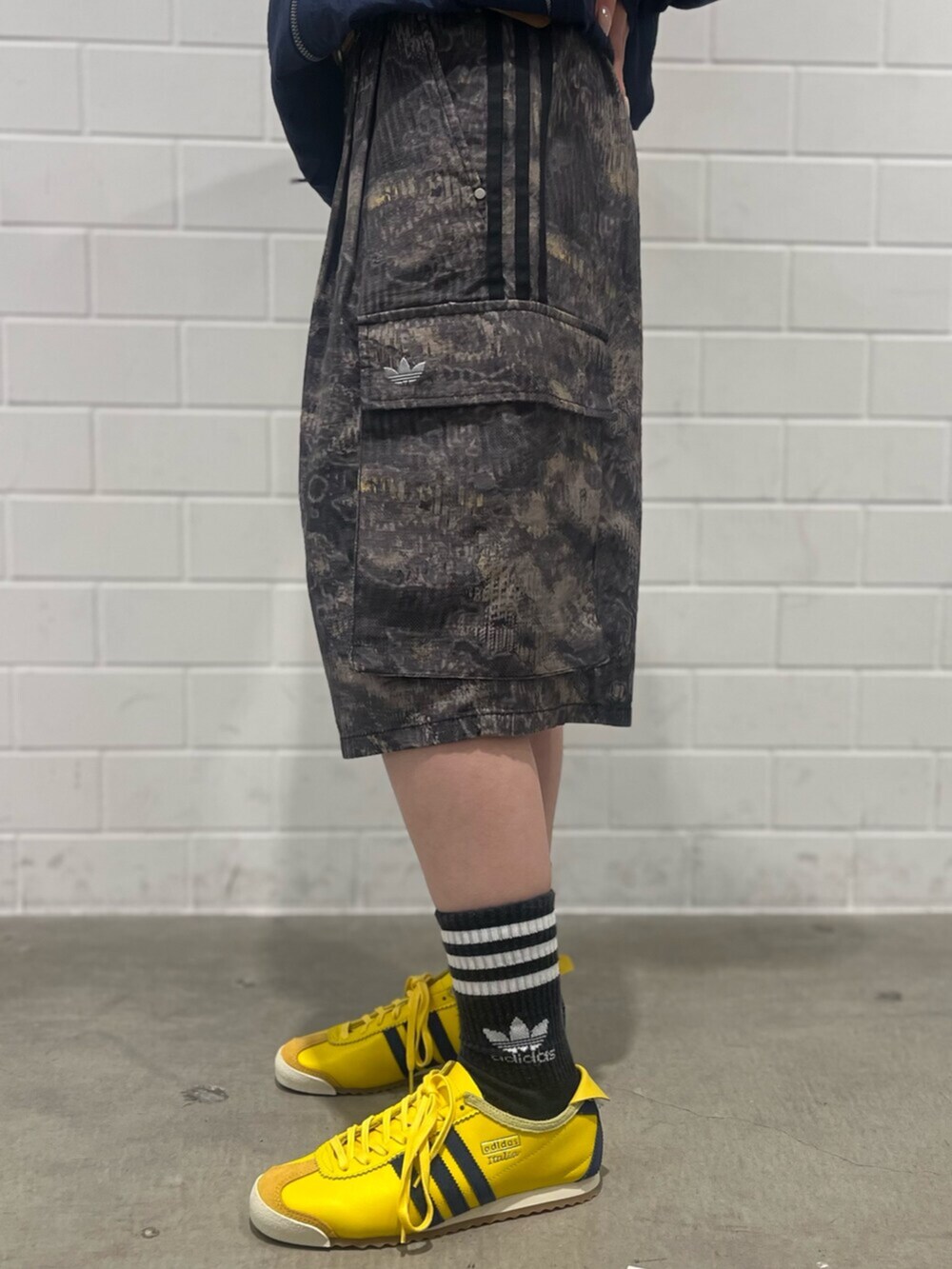 イエロー系のスニーカー、グレー系のカーゴパンツ、ブルー系のトップスを着用したレディースの春コーディネートの5枚目の写真