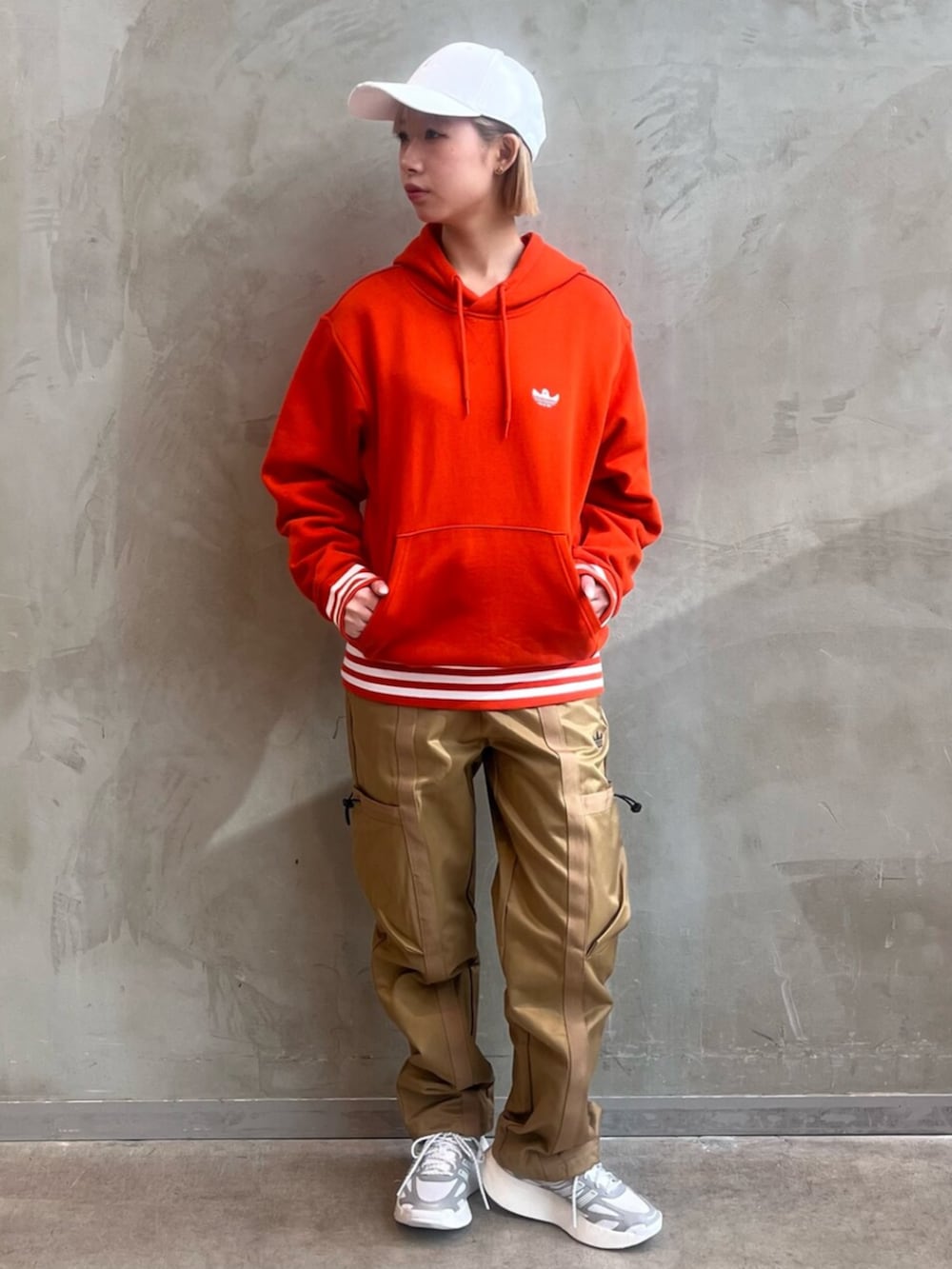 ブラウン系のカーゴパンツ、ホワイト系のシューズ、オレンジ系のパーカーを着用したレディースの冬コーディネートの2枚目の写真