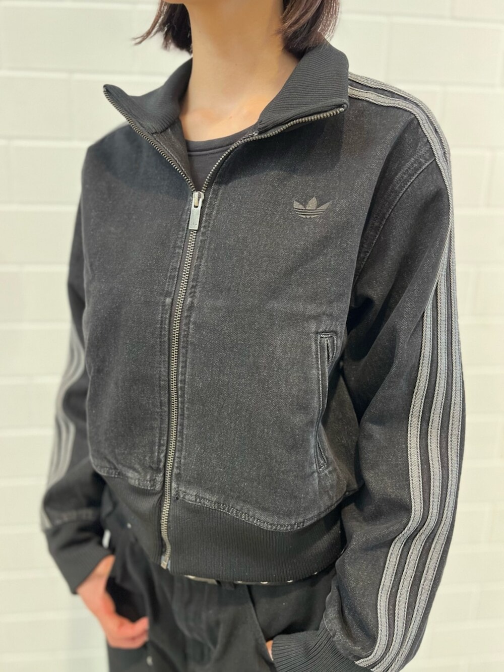 ブラック系のデニムジャケット、ホワイト系のスニーカー、ブルー系のアクセサリーを着用したレディースの春コーディネートの5枚目の写真