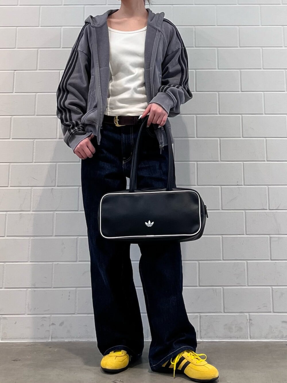 ブラック系のショルダーバッグ、イエロー系のスニーカー、グレー系のパーカーを着用したレディースの冬コーディネートの2枚目の写真