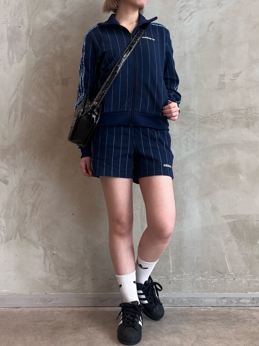 ブラック系のショルダーバッグ、ブラック系のスニーカー、ブルー系のトップスを着用したレディースの春コーディネートの2枚目の写真