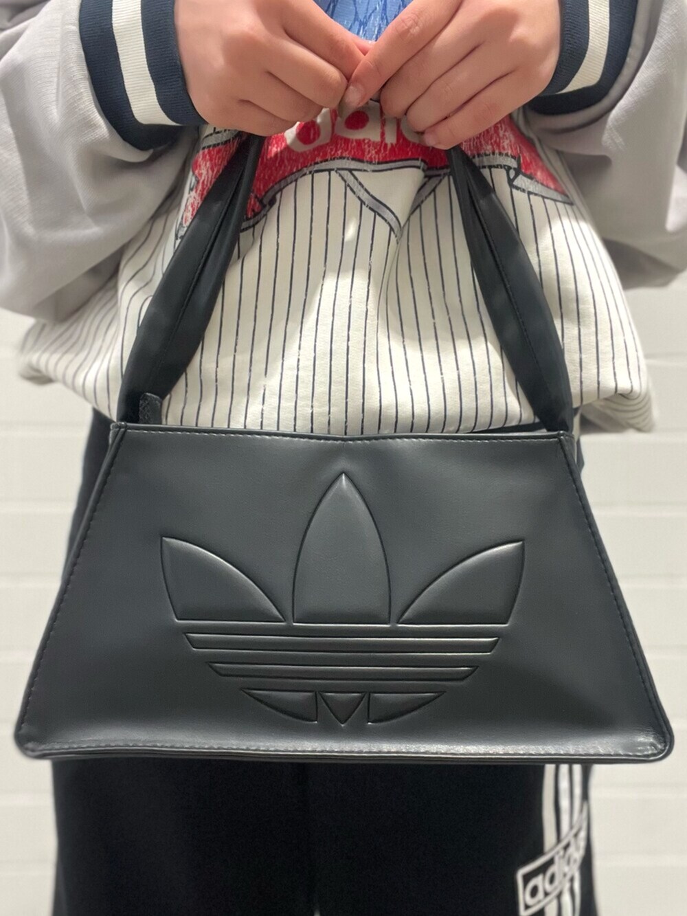 ブラック系のショルダーバッグ、レッド系のスニーカー、ブラック系のデニムパンツを着用したレディースの秋コーディネートの6枚目の写真