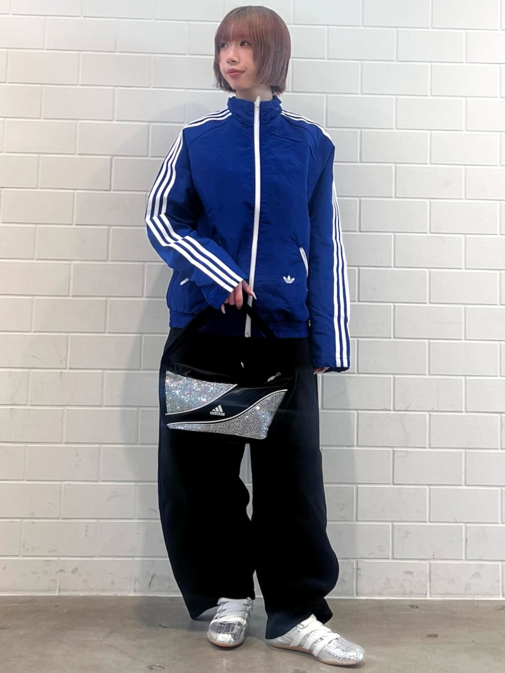 ブラック系のショルダーバッグ、シルバー系のスニーカー、ブルー系のナイロンジャケットを着用したレディースの春コーディネートの3枚目の写真