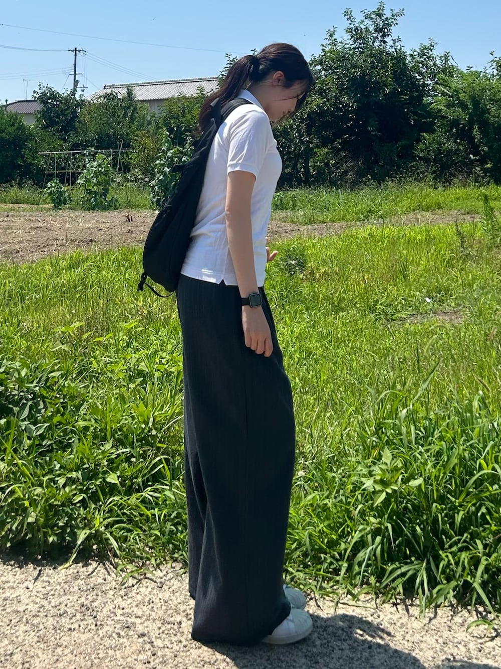 ホワイト系のスニーカー、ホワイト系のポロシャツ、ブラック系のボディバッグ/ウエストポーチを着用したレディースの夏コーディネートの3枚目の写真