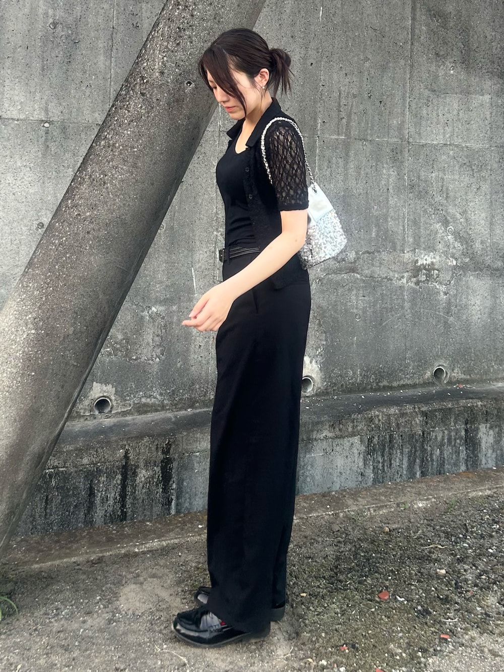 シルバー系のショルダーバッグ、ブラック系のポロシャツ、ブラック系のローファーを着用したレディースの夏コーディネートの2枚目の写真