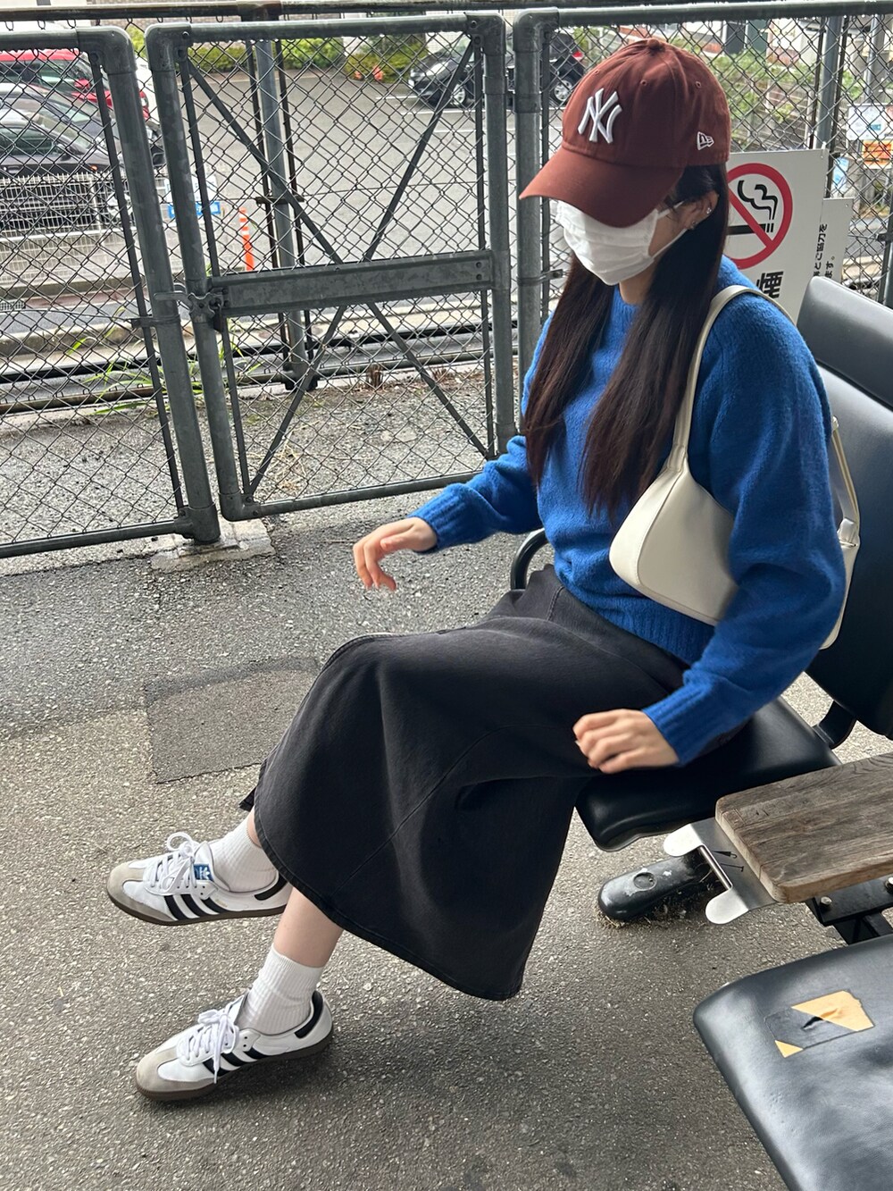 ホワイト系のスニーカー、ホワイト系のバッグ、ブラウン系のキャップを着用したレディースの秋コーディネートの2枚目の写真