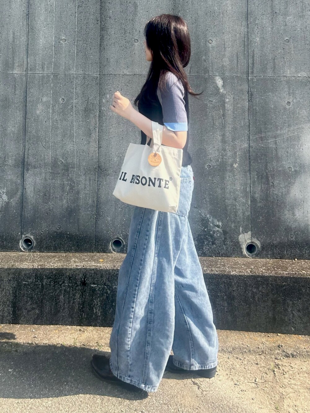 ブラック系のニット/セーター、ブラック系のローファー、ホワイト系のバッグを着用したレディースの夏コーディネートの2枚目の写真