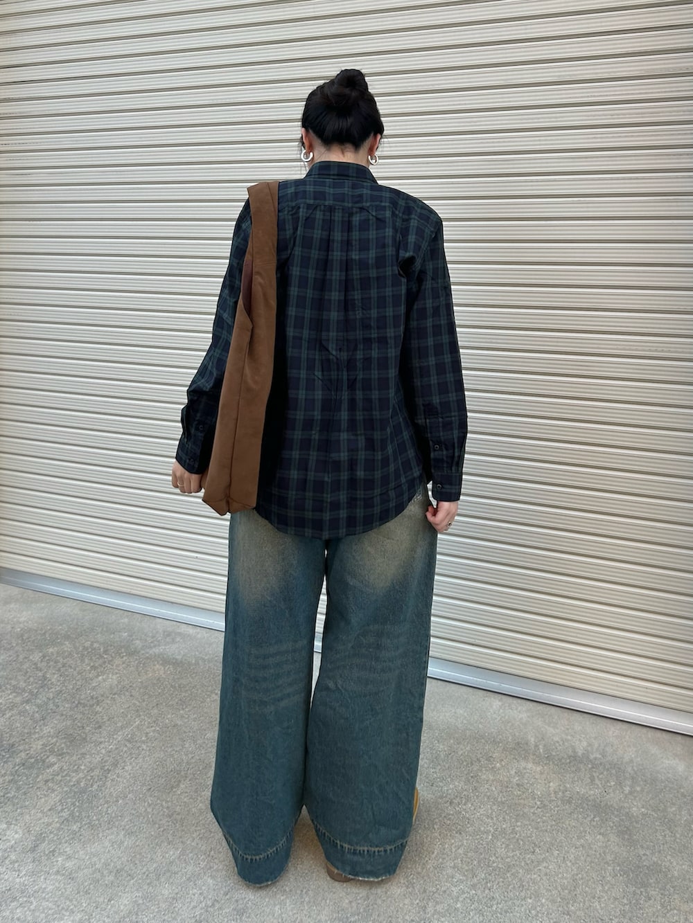 ブルー系のデニムパンツ、ブラウン系のトートバッグ、ベージュ系のドレスシューズを着用したレディースの秋コーディネートの3枚目の写真