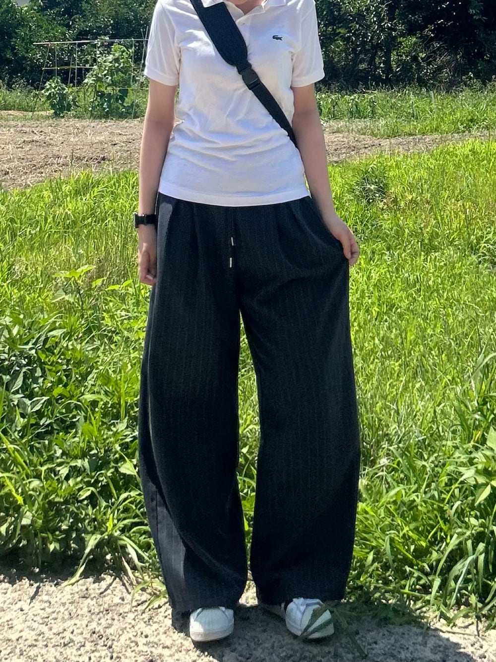 ホワイト系のスニーカー、ホワイト系のポロシャツ、ブラック系のボディバッグ/ウエストポーチを着用したレディースの夏コーディネートの4枚目の写真