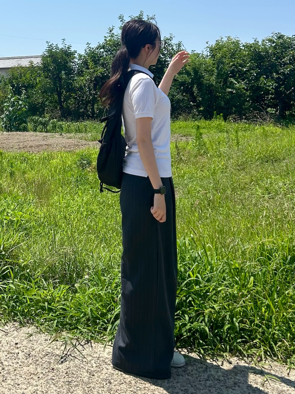 ホワイト系のスニーカー、ホワイト系のポロシャツ、ブラック系のボディバッグ/ウエストポーチを着用したレディースの夏コーディネートの2枚目の写真