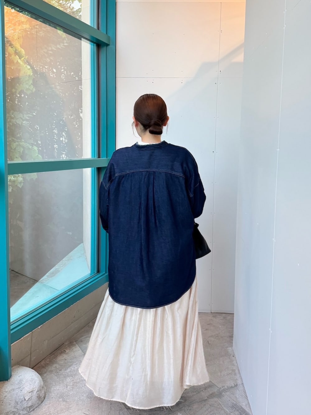 ブラック系のショルダーバッグ、ベージュ系のスカート、ブラック系のレインシューズを着用したレディースの秋コーディネートの3枚目の写真