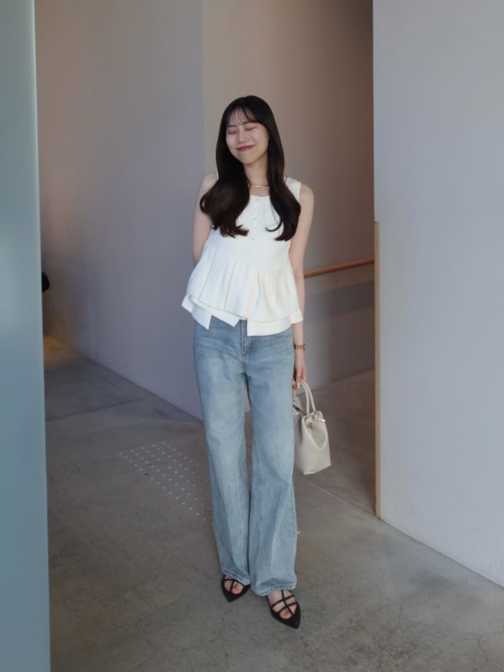 ホワイト系のニット/セーター、ブルー系のデニムパンツ、ホワイト系のショルダーバッグを着用したレディースの夏コーディネートの3枚目の写真