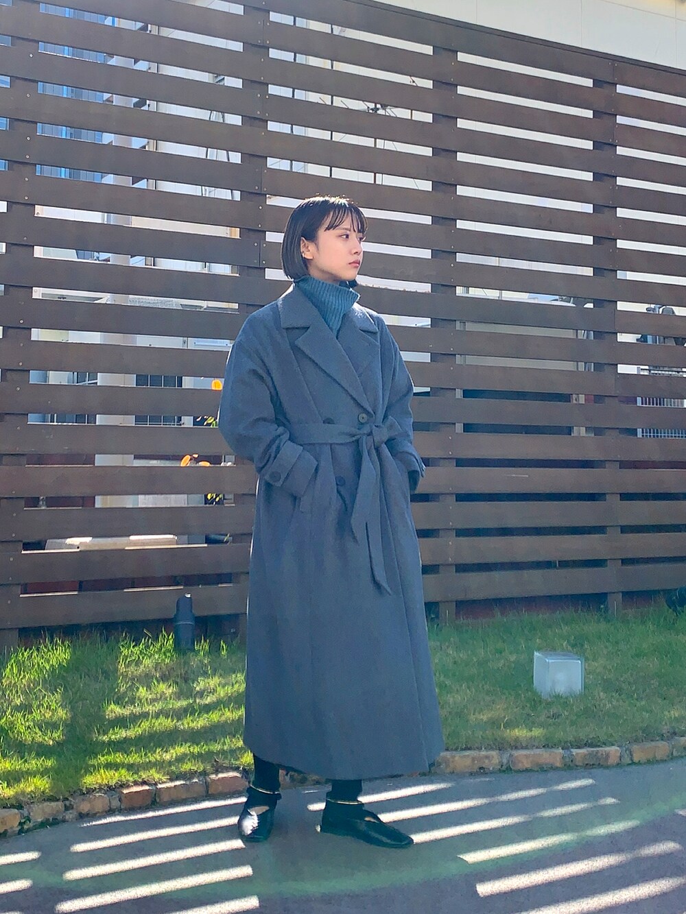 グレー系のチェスターコート、グレー系のニット/セーターを着用したレディースの秋コーディネートの2枚目の写真